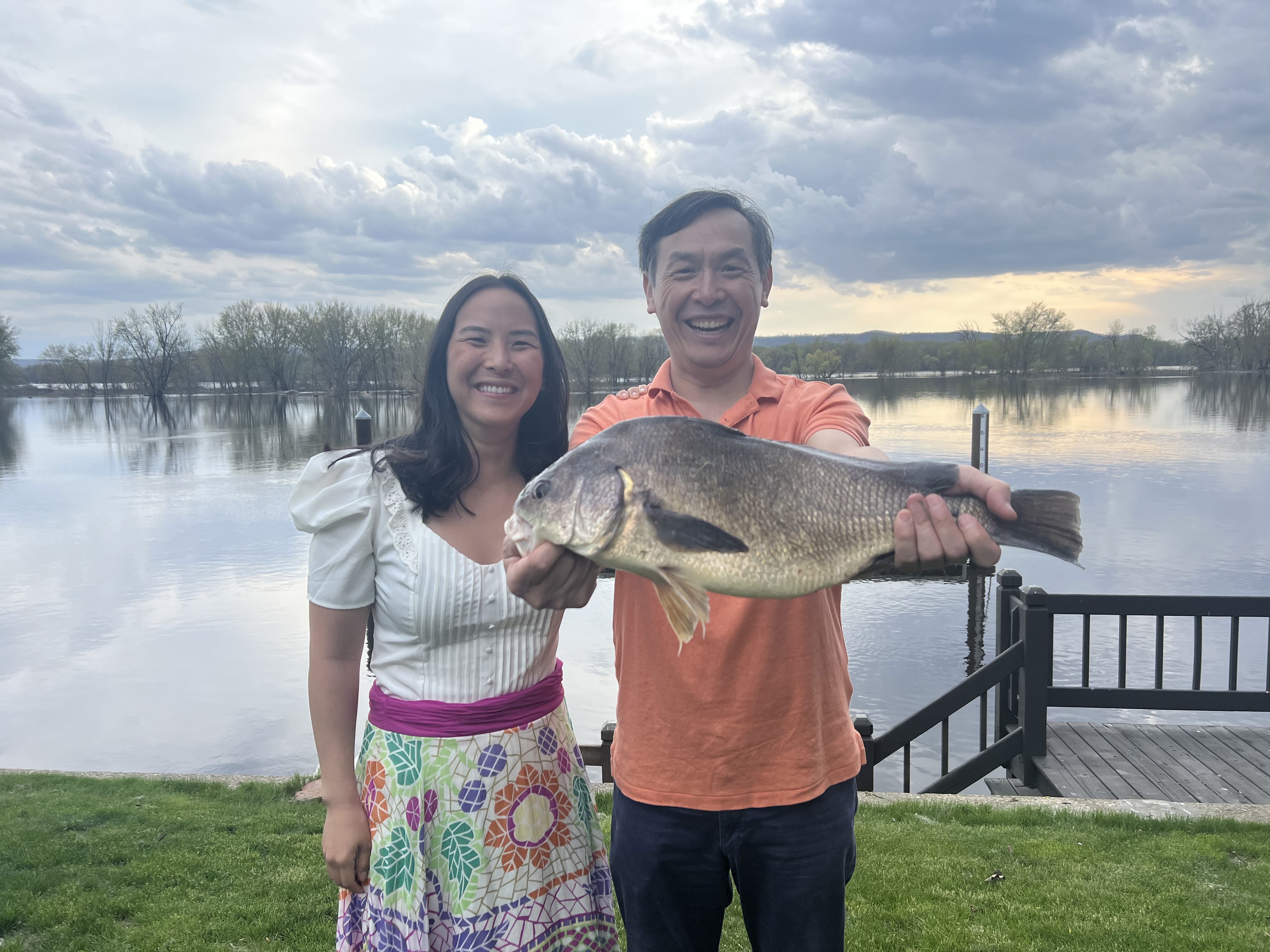 Amy Yin with her dad holding a fish by the Mississippi river